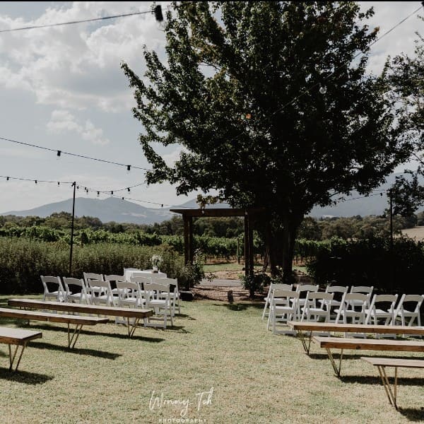 Outdoor Ceremony. Wooden benches and white chairs.