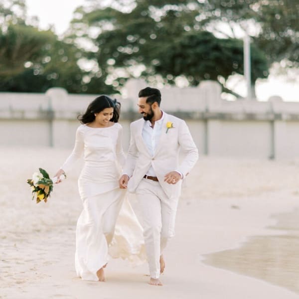 Couple running on the beach on their wedding day