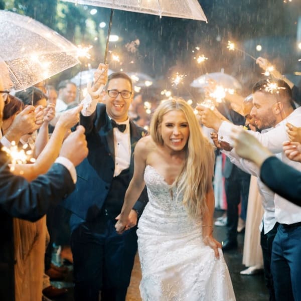 Couple having a sparkler exit in the rain