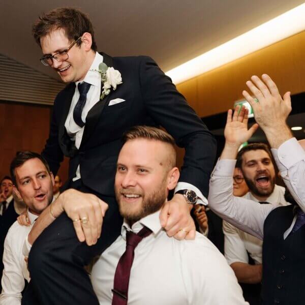 Groom on guests shoulders with a traditional dance