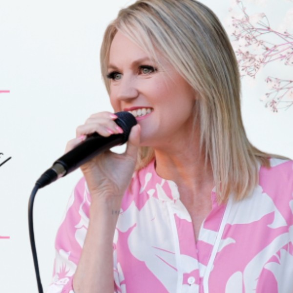 Shelley singing with a black microphone and a pink and white dress on