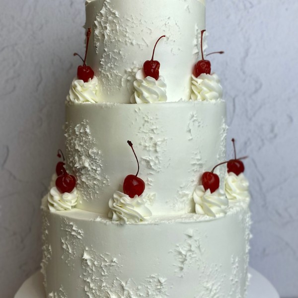 White cake with textured buttercream and maraschino cherries